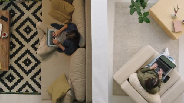 彼らのアパートでノートパソコンで作業壁によって区切られた若い男と女のトップビューショット — ストック動画