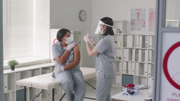 Panning Medium Bilde Sykepleier Med Beskyttende Ansikt Skjold Gir Vaksinasjonsdose – stockvideo