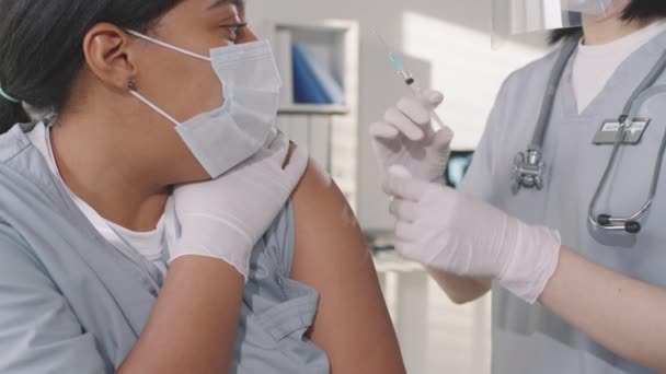 アフリカ系アメリカ人女性の病院労働者が同僚にワクチン接種用量を与えることでコロナウイルスに対するワクチン接種を受けるというスローモーション メディアの閉鎖 — ストック動画