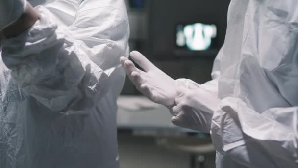 ミッドセクション閉じるとともに遅いです2人の著名な医師で暗い病院の部屋に身に着けています保護白い衣装と手袋 — ストック動画