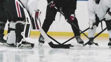 Tanınmayan erkek hokey oyuncularının düşük seviyeli yavaşlığı maçtan önce çubuklarını buza vurarak daireler çiziyor.