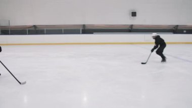 Yüksek açılı PAN şutu, yavaş hokey oyuncusuyla puck 'la puck' la paten kayıyor ve golü dinamik bir şekilde atıyor.
