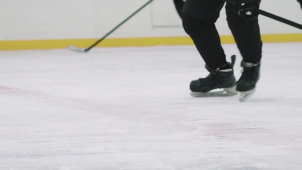 Nízký úhel PAN s pomalým nepoznatelným hokejista stávkující puk s holí a další hráči se snaží získat kontrolu nad ním, bruslení na vnitřní ledové aréně