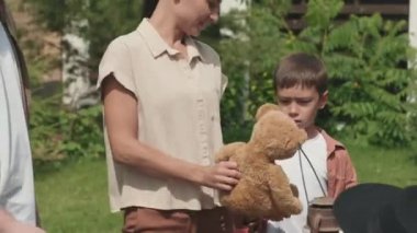  Eski oyuncaklara ve garaj satışında komşularının banliyödeki evlerinin bahçesinde tuttuğu diğer eşyalara bakan neşeli genç kadın ve çocuğun el kamerasıyla çekilmiş görüntüleri.