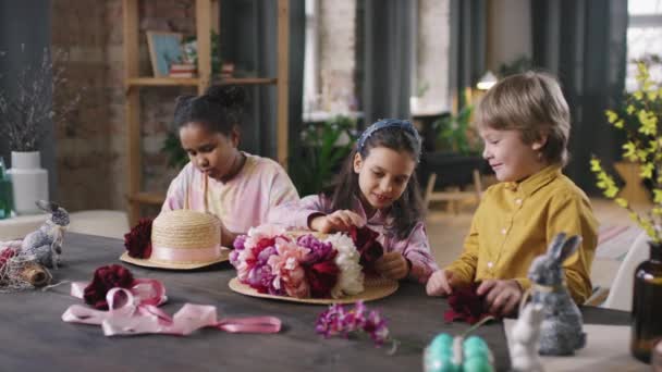 Orta Boy Çocukların Masada Oturup Paskalya Için Çiçeklerle Hasır Şapkalar — Stok video