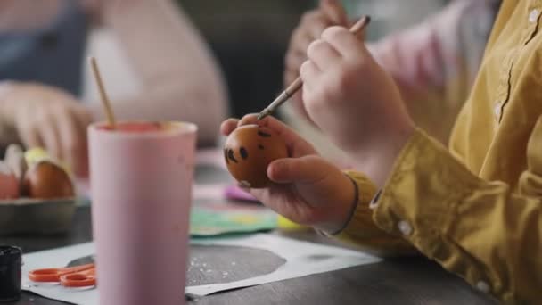 艺术课上用画笔和彩绘彩绘彩绘复活节彩蛋的可爱男孩的手的中间部分 — 图库视频影像