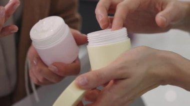 Güzellik salonundaki tanınmayan kadın müşterilerin yavaş çekim görüntüsü. Deneme şişesinden krem sürüyorlar.