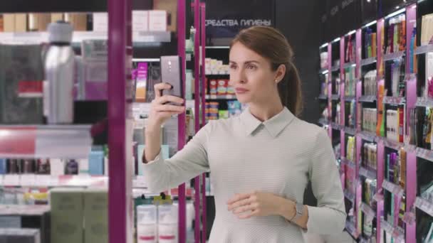 Güzel Bir Bayan Müşterinin Kozmetik Mağazasında Akıllı Telefondan Güzellik Ürünlerinin — Stok video