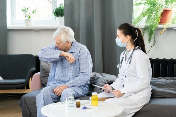 Jonge Vrouwelijke Huisarts Met Touchpad Kijken Naar Zieke Senior Man — Stockfoto