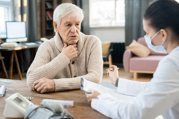 Kranker Älterer Mann Schaut Junge Ärztin Weißem Kittel Und Medizinischer — Stockfoto