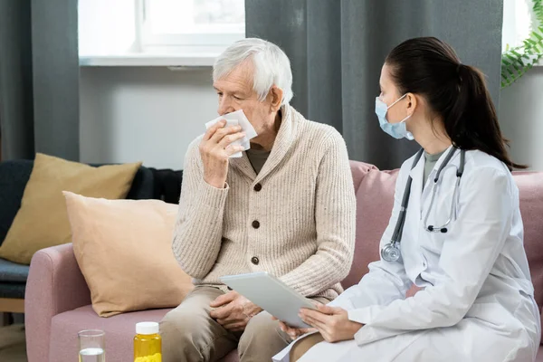 Junge Hausärztin Mit Digitalem Tablet Blickt Kranken Älteren Mann Mit — Stockfoto