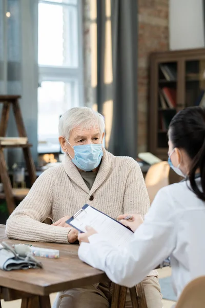 Kranker Älterer Mann Freizeitkleidung Und Schutzmaske Schaut Junge Ärztin Mit — Stockfoto