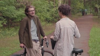 Kafkasyalı genç ve sportif çiftin yaz ormanlarında bisiklet sürerken çekilmiş yavaş çekimleri.