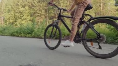 Parkta tek başına bisiklet süren ve yaz tatilinin tadını çıkaran tanınmayan bir gencin düşük seviyeli takibi.