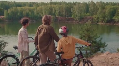 Güneşli bir günde bisiklet sürerken parkın tadını çıkaran aktif ebeveynlerin orta boy fotoğrafları.