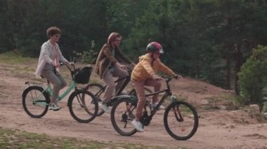 Aktif ebeveynlerin ve oğullarının yazın parkta at sürerken yavaş çekim görüntüleri.