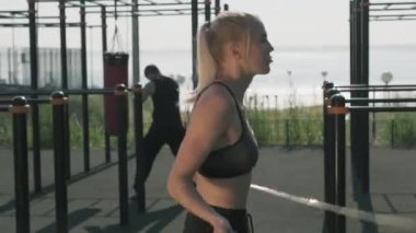 Sporcu yaz aylarında spor sahasında kum torbasıyla boks yaparken beyaz kadın sporcunun ip atlarken orta boy fotoğrafı.