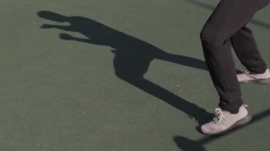 Tanınmayan erkek bacakları ve yazın spor sahasında boksörlerin gölgesi.