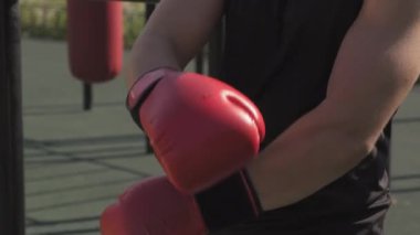 Kafkasyalı ciddi bir sporcunun boks eldivenlerini takıp, kameraya bakarak, açık havada antrenman yaparken çekilmiş yakın plan portresi.
