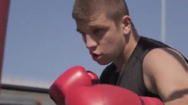 Beyaz tenli genç boksör kum torbasının el bilgisayarı görüntüsü açık havada.