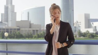 Şehir merkezindeki köprüde önemli bir telefon görüşmesi yapan ciddi bir iş kadınının orta boy fotoğrafı.