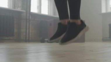 Siyah spor ayakkabılı, tanınmayan kadın bacaklı, dumanlı tavan arasında ip atlayan düşük seviyeli yavaş kadın.