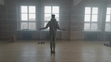 Gri eşofmanlı yavaş genç sporcunun dumanlı tavan arası odasında pencerenin önüne ip atlamasıyla tam görüş.