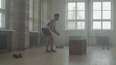 Yavaş çekimde, Afrikalı-Amerikalı sporcunun biraz esneme hareketleri, sonra da kapalı alanda dayanıklılık egzersizleri yapması, dumanlı çatı katı tarzı spor salonu.