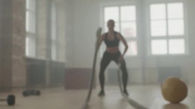 Ağır çekimde, dumanla dolu boş çatı katı tarzı bir spor salonunda güçlü bir spor kadını eğitiminde bulanıklaştı.