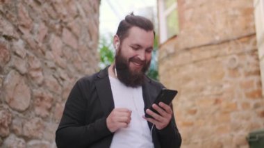 Düşük açılı, mutlu sakallı bir adamın cep telefonuyla görüntüsü.