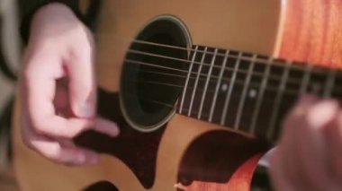 Akustik gitar çalan tanınmayan bir erkek müzisyenin yakın plan el bilgisayarı takibi