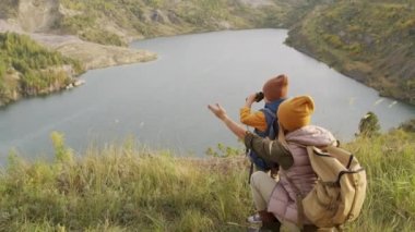 Yürüyüş sırasında taş ocağına bakan yeşil tepenin manzarasının keyfini çıkaran genç bir kadın ve küçük şirin bir çocuğun el kamerasıyla çekilmiş yavaş el kamerası görüntüleri.