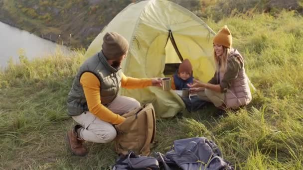 中镜头的父亲 女人和可爱的5岁儿子一起在青山上露营 俯瞰着湖面 快乐的大胡子男人从背包里拿出真空瓶和杯子 — 图库视频影像