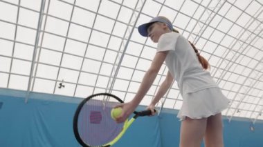 Düşük açılı orta açı, profesyonel tenis oynayan, tenis oynayan, tenis oynayan ve kapalı sahada tenis oynayan küçük bir kız.