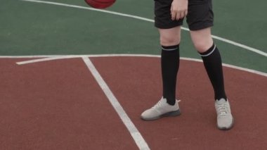 Kızıl saçlı, sakallı, basketbol oynayan ve kasvetli bir günde sahada basket oynayan genç bir adamın el kamerası takibi.