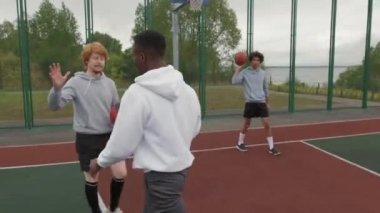 Neşeli genç adamın arkadaşına beşlik çakarken ve kasvetli bir günde dışarıda basketbol oynarken elde çekilmiş bir fotoğrafı.