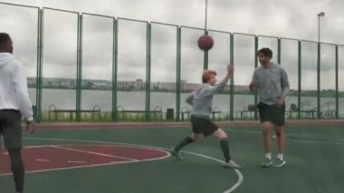 Kasvetli bir günde sokak basketbolu oynayan dört gencin el kamerasıyla çekilmiş fotoğrafı.