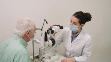 Üst düzey bir adamın gözlüğünü çıkarırken ve modern klinikteki göz muayenesinde gözlüğünü phoropter tarafından kontrol edilirken orta boy bir fotoğraf.