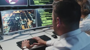 Modern ofis bilgisayarlarının önünde oturan olgun bir adam ve genç bir kadının bilgisayar korsanlarıyla savaşırken çekilmiş görüntüleri.