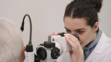 Göz kontrolü makinesiyle çalışan genç bayan göz doktorunun yakın çekimi. Hasta için görme kontrolü yapıyor.