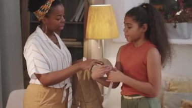 Orta boy Afro-Amerikalı bir kadının 10 yaşındaki kızını okula hazırladığı sabah sarılıp vedalaştığı fotoğraf.