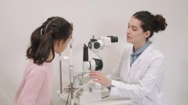 Küçük güzel bir kızın düzenli kontrol için kadın optometrist doktoru ziyaret ettiği orta boy bir fotoğraf. Sağlık ve İlaç kavramı