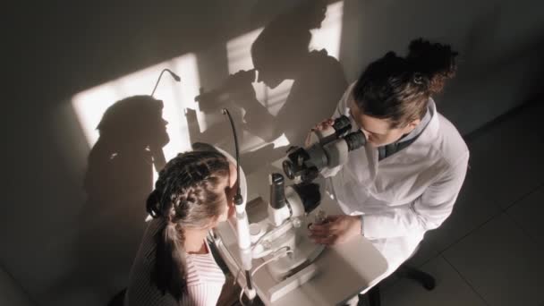 Aufnahme Von Oben Augenärztin Lässt Kleine Mädchen Sonnendurchfluteter Arztpraxis Phoropter — Stockvideo