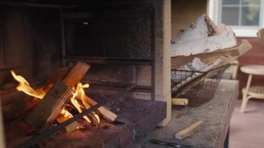 Tanımlanamayan bir insanın elini kapayarak şöminenin içindeki güzel ateşe odun koyuyor.