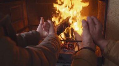 Tanımlanamayan bir çocuk ve yaşlı bir adamın şöminenin önünde durup ateş başında ellerini ısıtmasının görüntüsü.
