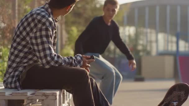 Handheld Slow Shot Adolescente Montando Monopatín Hacia Sus Amigos Intercambiando — Vídeo de stock