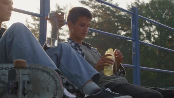 Handhållen Slowmo Skott Tonåringar Sitter Toppen Ramp Skatepark Och Dricksvatten — Stockvideo