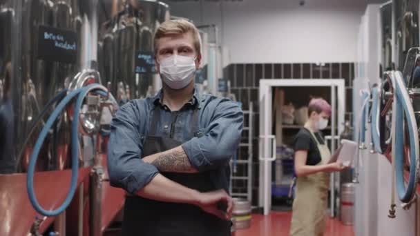身着防护面罩 双手交叉看着相机站在一边 女性同事在幕后控制啤酒生产过程的残暴酿酒师慢动作媒体画像 — 图库视频影像
