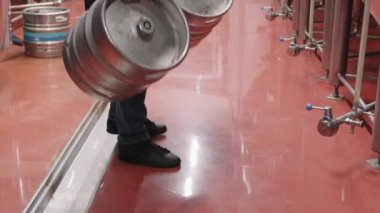 Bira fabrikası boyunca ağır metal bira fıçıları taşıyan tanınmayan bir erkek bira fabrikası işçisinin yavaş çekimleri.