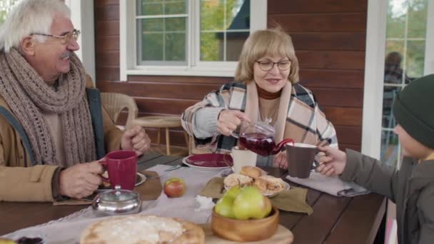 미디엄 캅카스 조부모는 재킷을 테라스에 식탁에 마시고 집에서 파이를 수다를 — 비디오